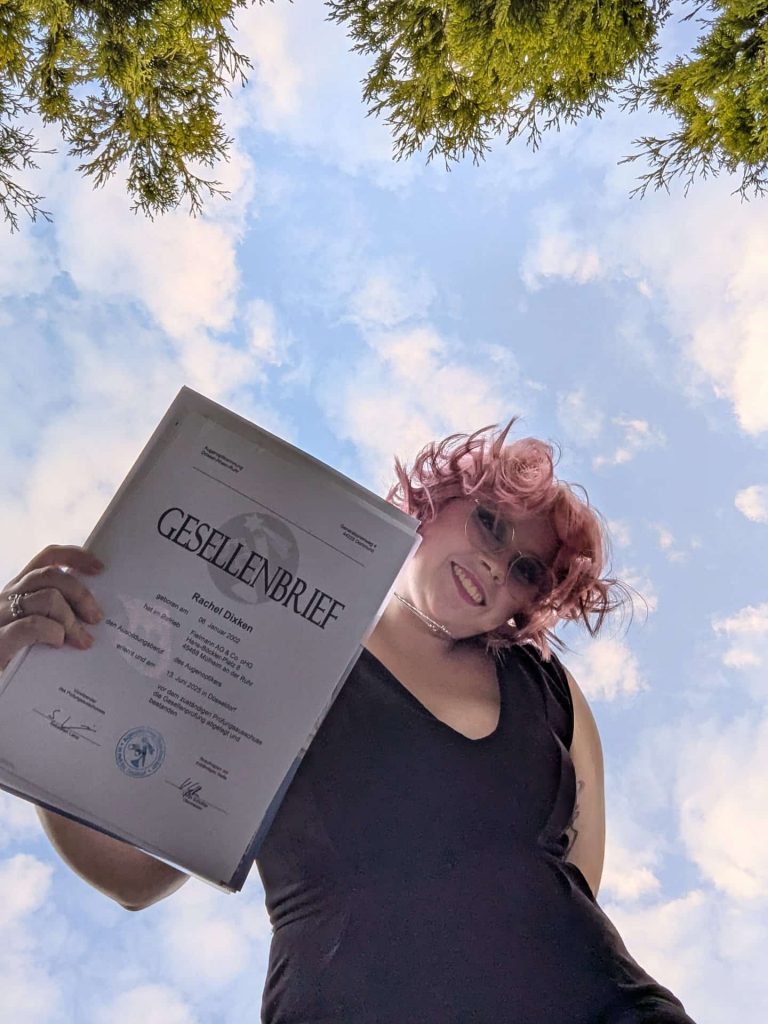 Verfasserin lächelnd von unten Fotographiert mit einem gesellenbrief in der hand
